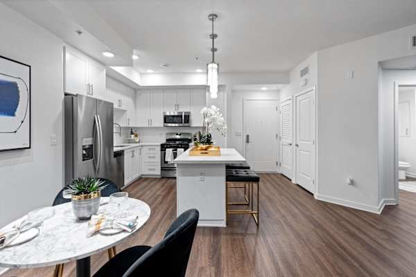 an open kitchen and dining room with white cabinets and stainless steel appliances
